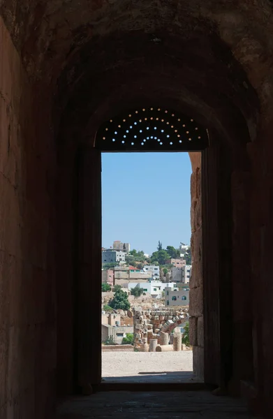 Jordanie : l'horizon de Jerash moderne vu à travers une porte décorée du Théâtre du Nord, construit en 165 après JC et utilisé comme scène de spectacle et la salle du conseil municipal, dans la ville archéologique de Gerasa — Photo