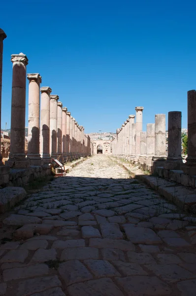 Jordânia: o Cardo Maximus, a Rua Colonnaded, que foi a espinha arquitetônica e ponto focal da cidade arqueológica de Jerash, eo Portão do Norte no fundo — Fotografia de Stock