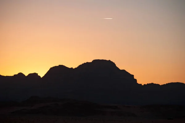 요르단: 사막와 디 럼에서 산의 어두운 개요에 불타는 일몰, 사암과 화강암 바위를 잘라 고 화성의 행성 처럼 보이는 달의 계곡 — 스톡 사진