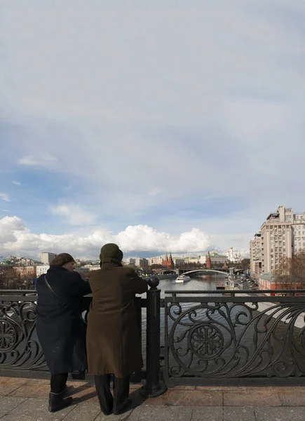 Russia: two old Russian women looking the skyline of Moscow with view of the fortified complex of the Kremlin from the Patriarch Bridge on the Moskva River