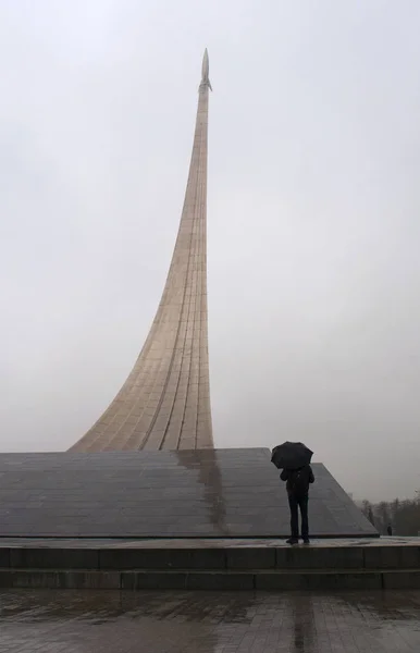 Moscou, Rússia: homem com guarda-chuva em frente ao Monumento aos Conquistadores do Espaço, um foguete em sua rampa de lançamento construída em 1964 para celebrar conquistas do povo soviético na exploração espacial, dentro cuja base é o Museu de Cosmonáutica — Fotografia de Stock