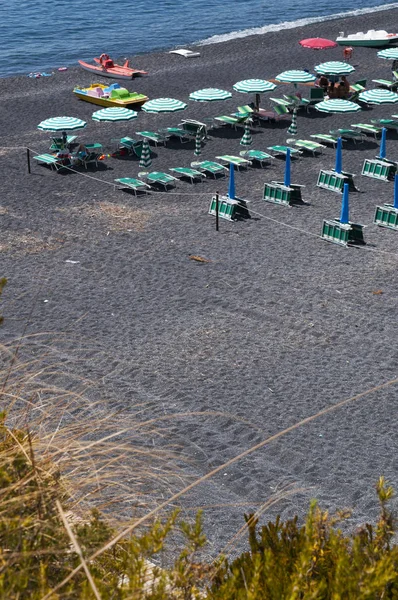 Calabria: una delle spiagge nere vicino alla cittadina di San Nicola Arcella, con ombrelloni e sdraio di fronte al Mar Tirreno — Foto Stock