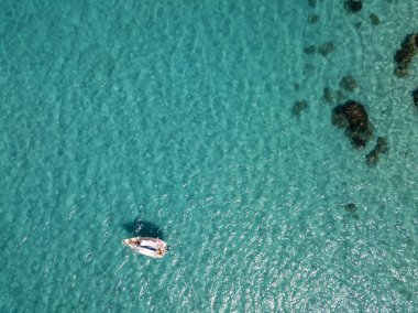 Havadan görünümü şeffaf bir denizde yüzen bir demirli teknenin. Dalış dinlenme ve yaz tatil. İtalyan kıyıları, plajları ve kayalar