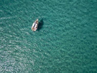 Havadan görünümü şeffaf bir denizde yüzen bir demirli teknenin. Dalış dinlenme ve yaz tatil. İtalyan kıyıları, plajları ve kayalar
