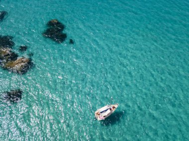 Havadan görünümü şeffaf bir denizde yüzen bir demirli teknenin. Dalış dinlenme ve yaz tatil. İtalyan kıyıları, plajları ve kayalar