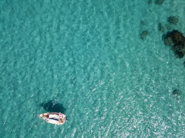 Havadan görünümü şeffaf bir denizde yüzen bir demirli teknenin. Dalış dinlenme ve yaz tatil. İtalyan kıyıları, plajları ve kayalar