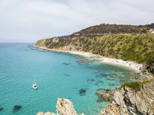 Vista aérea de un barco amarrado flotando en un mar transparente. Playa con promontorio con vistas al mar. Zambrone, Calabria, Italia — Foto de Stock