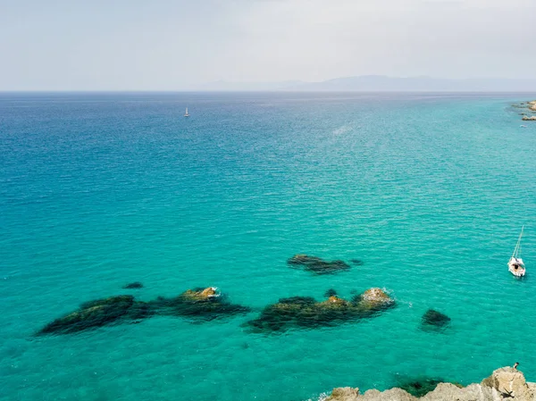 Aerial view of a moored boat floating on a transparent sea. Diving relaxation and summer vacations. Italian coasts, beaches and rocks — Stock Photo, Image