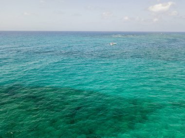 Havadan görünümü şeffaf bir denizde yüzen tekne. Dalış dinlenme ve yaz tatil. İtalyan kıyıları, plajları ve kayalar