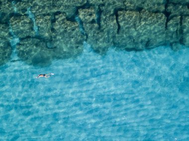 Aerial view of rocks on the sea. Overview of seabed seen from above, transparent water. Swimmers, bathers floating on the water clipart