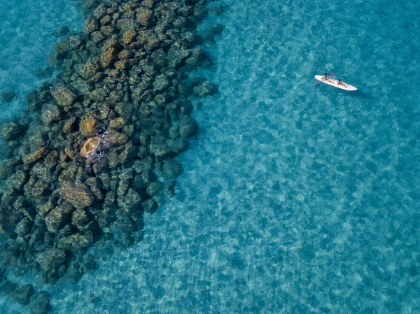 Aerial view of a canoe in the water floating on a transparent sea. Bathers at sea. Zambrone, Calabria, Italy. Diving relaxation and summer vacations. Italian coasts, beaches and rocks — Stock Photo, Image