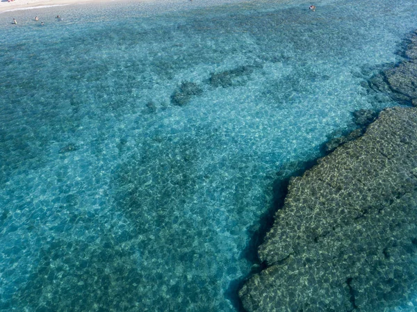 Aerial view of rocks on the sea. Overview of seabed seen from above, transparent water. Swimmers, bathers floating on the water — Stock Photo, Image