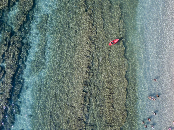 Luftaufnahme eines Kanus im Wasser, das auf einem transparenten Meer schwimmt. Badende auf See. Zambrone, Kalabrien, Italien. Taucherentspannung und Sommerferien. Italienische Küsten, Strände und Felsen — Stockfoto