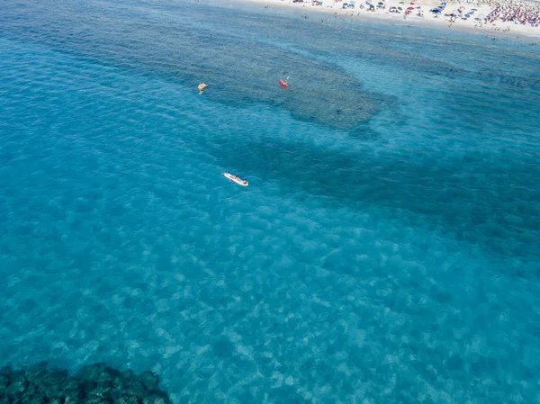 Αεροφωτογραφία του κανό στο νερό κυμαινόμενο σε μια διάφανη θάλασσα. Οι λουόμενοι στη θάλασσα. Zambrone, Καλαβρία, Ιταλία. Καταδύσεις χαλάρωση και καλοκαιρινές διακοπές. Ιταλικές ακτές, παραλίες και βράχια — Φωτογραφία Αρχείου