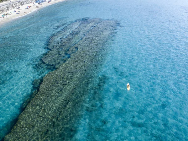 Αεροφωτογραφία του κανό στο νερό κυμαινόμενο σε μια διάφανη θάλασσα. Οι λουόμενοι στη θάλασσα. Zambrone, Καλαβρία, Ιταλία. Καταδύσεις χαλάρωση και καλοκαιρινές διακοπές. Ιταλικές ακτές, παραλίες και βράχια — Φωτογραφία Αρχείου