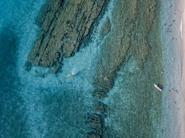 Vista aérea de rocas sobre el mar. Visión general del fondo marino visto desde arriba, agua transparente. Nadadores, bañistas flotando en el agua — Foto de Stock
