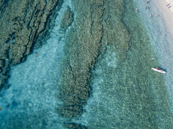 Aerial view of a canoe in the water floating on a transparent sea. Bathers at sea. Zambrone, Calabria, Italy. Diving relaxation and summer vacations. Italian coasts, beaches and rocks — Stock Photo, Image