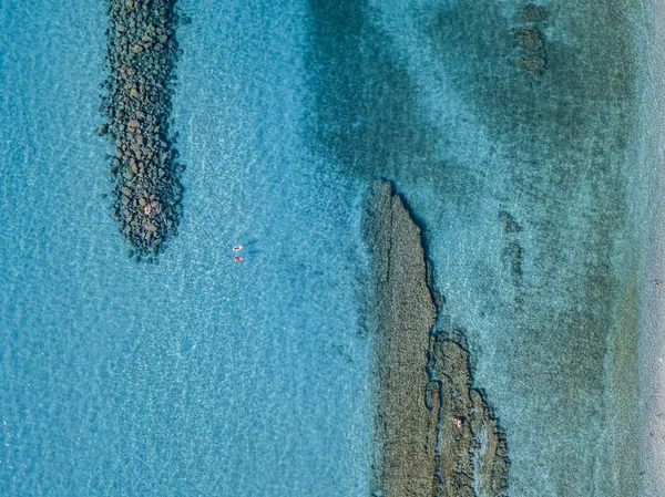 Vue aérienne d'un canot dans l'eau flottant sur une mer transparente. Des baigneurs en mer. Zambrone, Calabre, Italie. Détente de plongée et vacances d'été. Côtes, plages et rochers italiens — Photo