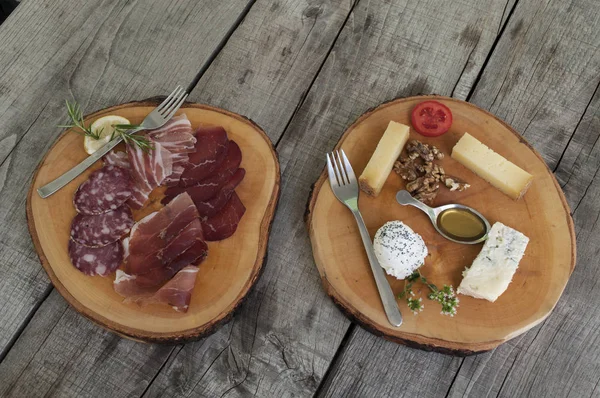 Salami and cheese wooden plates on a wooden table — Stock Photo, Image