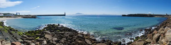 Espanha: vista da Playa Chica, a pequena praia no final do porto de Tarifa, na costa mais meridional de frente para o Estreito de Gibraltar e Marrocos, com a estátua de Sagrado Corazon de Jesus em Punta del Santo — Fotografia de Stock