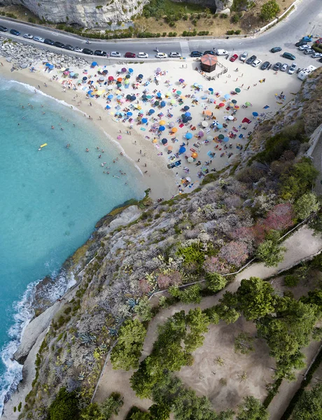 Vista aérea de uma praia com guarda-chuvas e banhistas. Promontório do Santuário de Santa Maria dell 'Isola, Tropea, Calábria, Itália — Fotografia de Stock