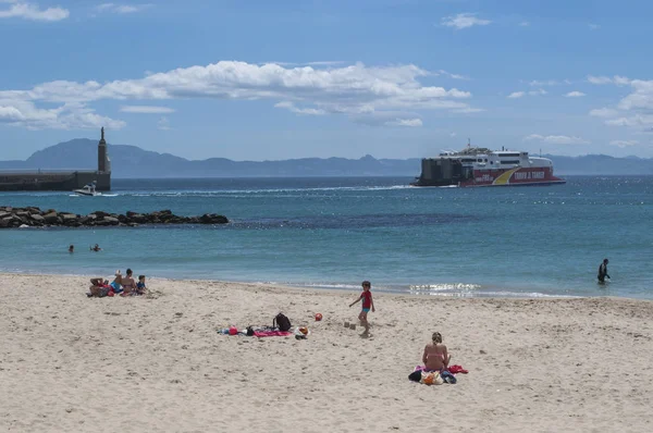 Espagne : personnes à Playa Chica, petite plage au bout du port de Tarifa face au détroit de Gibraltar et au Maroc, avec vue sur la statue de Sagrado Corazon de Jesus à Punta del Santo — Photo