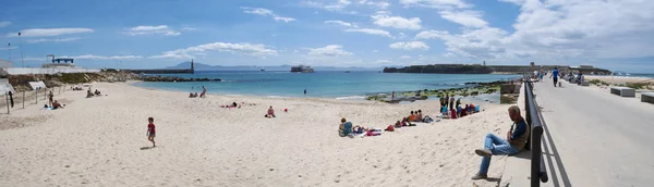 Испания: люди на Playa Chica, маленький пляж в конце порта Фафа, выходящий на проливы Джибриль и Моррелло, с видом на статую Саградо Корасон де Хесус в Пунта-дель-Санто — стоковое фото