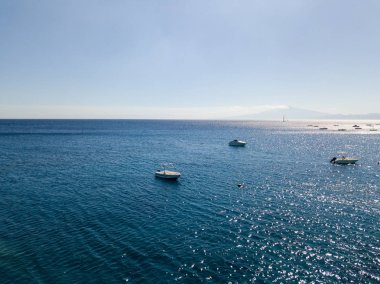 Havadan görünümü şeffaf bir denizde yüzen bir demirli teknenin. Dalış dinlenme ve yaz tatil. İtalyan kıyıları, plajları ve kayalar. Etna yanardağı içinde belgili tanımlık geçmiş