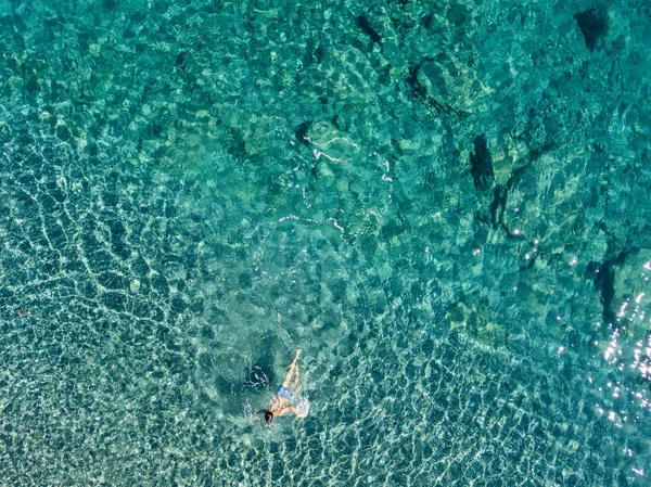 Luftaufnahme von Felsen auf dem Meer. Übersicht des Meeresbodens von oben gesehen, transparentes Wasser. Schwimmer, Badende, die auf dem Wasser schwimmen. — Stockfoto