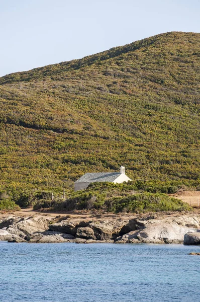 Córcega: vista de la Capilla Santa María, una pequeña iglesia rodeada de maquis mediterráneos, vista desde la Plage de Santa Maria, playa de Santa María, en el Cap Corse — Foto de Stock