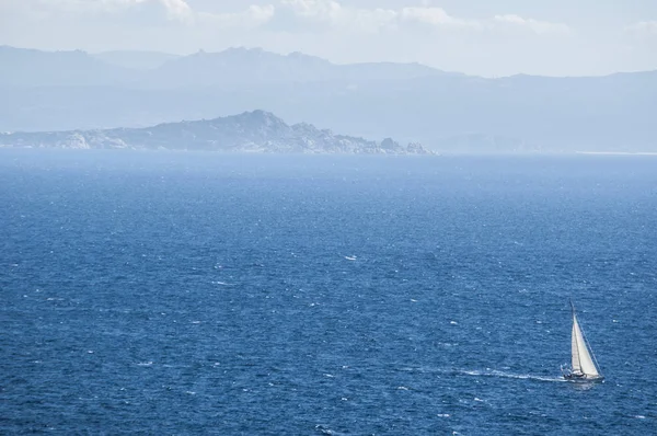 Corsica: a sailboat sailing in the Strait of Bonifacio, the stretch of sea between Corsica and Sardinia which divides the Tyrrhenian Sea from the western Mediterranean Sea — Stock Photo, Image