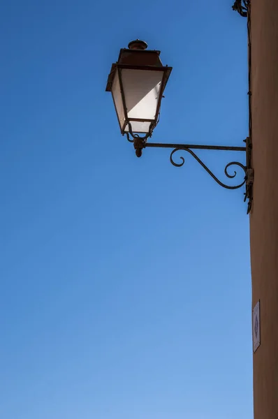 A wrought-iron street lamp and a blue sky in the background