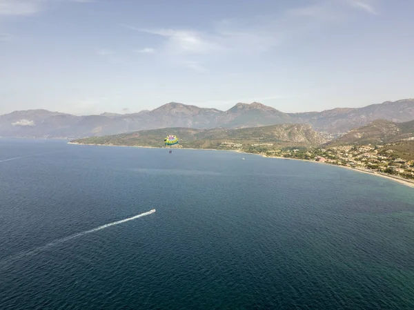 Aerial view of people practicing parasaling, parachutes dragged by a motorboat. Coast of Corsica, France. Saint Florent