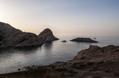 Kapalı sahil Ile de la Pietra (taş Adası), Ile-Rousse (Red Island), Upper Corsica ünlü bir şehir rocky promontory gün batımında Akdeniz'de yelken yelkenli
