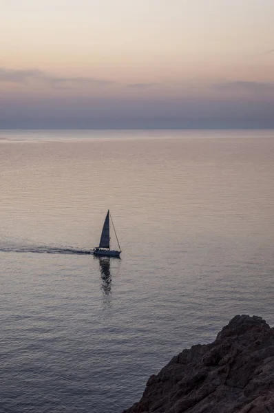 A sailboat sailing in the Mediterranean Sea at sunset off the coast of Ile de la Pietra (Stone Island), the rocky promontory of Ile-Rousse (Red Island), a famous city of the Upper Corsica — Stock Photo, Image