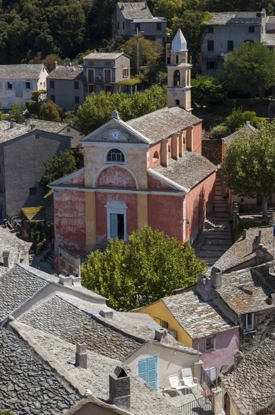 Κορσική: το ροζ ζωγραφισμένα εκκλησία του Saint Julie (Xvi αιώνα) στον ορίζοντα Nonza, χωριό για την δυτική ακτή της Cap Corse με παλιά σπίτια χτισμένο πάνω στους βράχους στην κορυφή 100 μέτρα στη θάλασσα — Φωτογραφία Αρχείου
