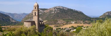 Corsica: panoramic view of the 16th century Church of Saint Martin in Patrimonio, a little town of Haute Corse, surrounded by green hills and vineyards  clipart