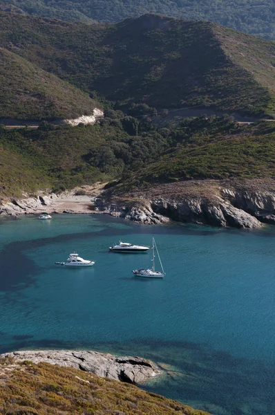 Córcega: barcos en las aguas cristalinas de Anse dAliso o Plage dAlisu, una de las playas más remotas del lado occidental de Cap Corse, península famosa por su paisaje salvaje —  Fotos de Stock