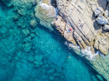 Denizde hava görünümünü taş. Yüzücüler, su üzerinde yüzen yıkananlara. Havlu üzerinde güneşlenme insanlar