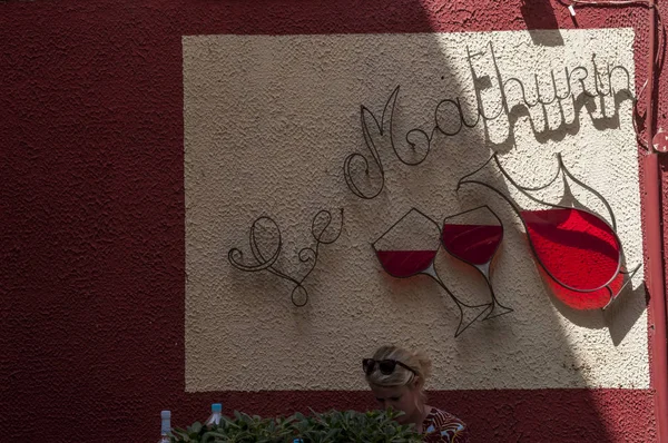 Córcega: una mujer sentada en uno de los muchos bares de vinos en las callejuelas de Saint-Florent, popular lugar de vacaciones de verano en la costa occidental del Alto Corse conocido como el corse Saint-Tropez — Foto de Stock