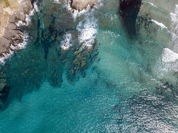 Aerial view of rocks on the sea. Overview of seabed seen from above, transparent water. Swimmers, bathers floating on the water