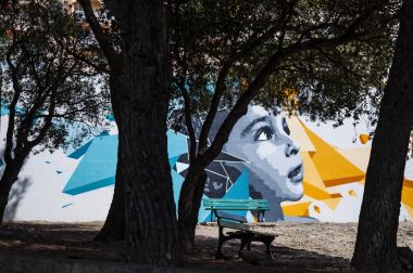 Korsika, 28/08/2017: Furiani bir halk alanında bir ağacın gölgesi altında bir tezgah, Haute Corse küçük kasaba, bir duvarda büyük bir murales ile