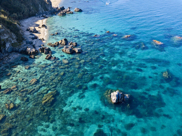 Вид с воздуха на пляж Тропеа, кристально чистую воду и скалы, которые появляются на пляже. Кальделла, Италия
