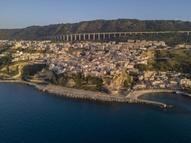 Pizzo Calabro, rıhtım, kale, Calabria, İtalya turizmi. Deniz kenarındaki küçük Pizzo Calabro kasabasının panoramik manzarası. Kayalıklardaki evler. Uçurumun kenarında Aragon kalesi duruyor. Gün batımında deniz önü