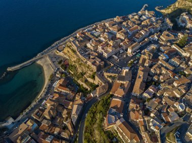 Pizzo Calabro, rıhtım, kale, Calabria, İtalya turizmi. Deniz kenarındaki küçük Pizzo Calabro kasabasının panoramik manzarası. Kayalıklardaki evler. Uçurumun kenarında Aragon kalesi duruyor. Gün batımında deniz önü