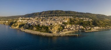 Pizzo Calabro, rıhtım, kale, Calabria, İtalya turizmi. Deniz kenarındaki küçük Pizzo Calabro kasabasının panoramik manzarası. Kayalıklardaki evler. Uçurumun kenarında Aragon kalesi duruyor. Gün batımında deniz önü