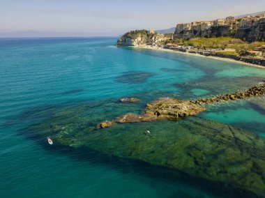 Şeffaf bir denizde yüzen, şnorkelle yüzen bir sörf tahtasının havadan görüntüsü. Denizde yıkanır. Tropea, Calabria, İtalya. Dalış ve yaz tatilleri. İtalyan kıyıları, plajları ve kayaları.