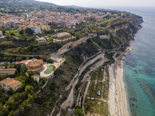 Aerial view of the Calabrian coast, villas and resorts on the cliff. Transparent sea and wild coast. Locality of Riaci near Tropea, Calabria. Italy