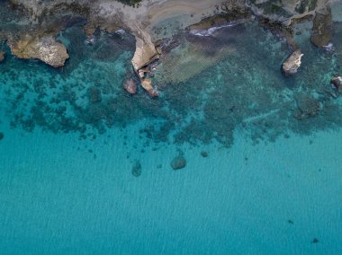 Denizden yükselen kayalar, yukarıdan görünen deniz yatağı, şeffaf su ve plaj manzarası.