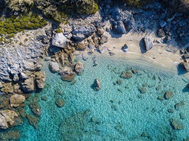 Tropea sahilinin hava manzarası, kristal berrak su ve sahilde ortaya çıkan kayalar. Calabria, İtalya. Yüzücüler, suda yüzen banyocular. Calabria kıyıları